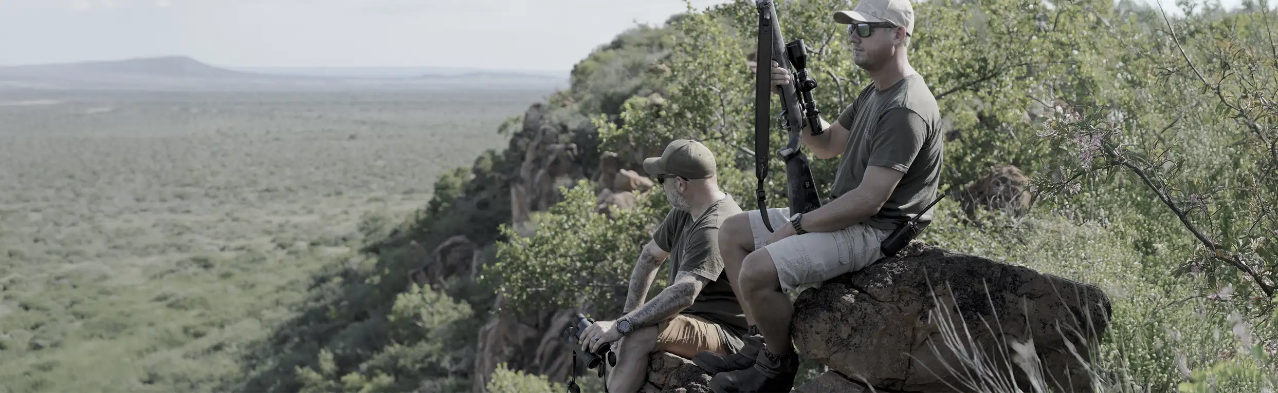 Hunters surveying open countryside with DDoptics binoculars and equipment